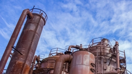 Eine fossile Industrieanlage vor blauem Himmel mit hellen Wolke